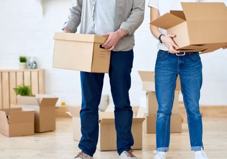 Mudanças residenciais: casal segurando caixas de papelão em mudança.