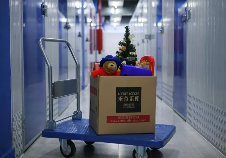 Carrinho de transporte com caixa de itens encima em galeria de armazenamento.