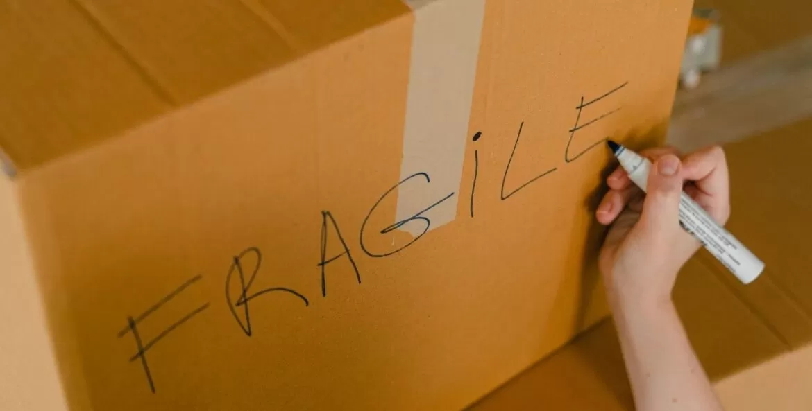 Como embalar produtos frágeis: pessoa escrevendo frágil em caixa.