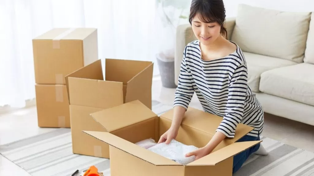 Mulher embalando coisas em caixa.