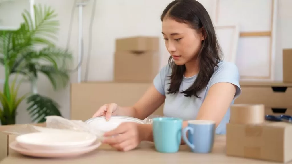 Mulher embalando louças.